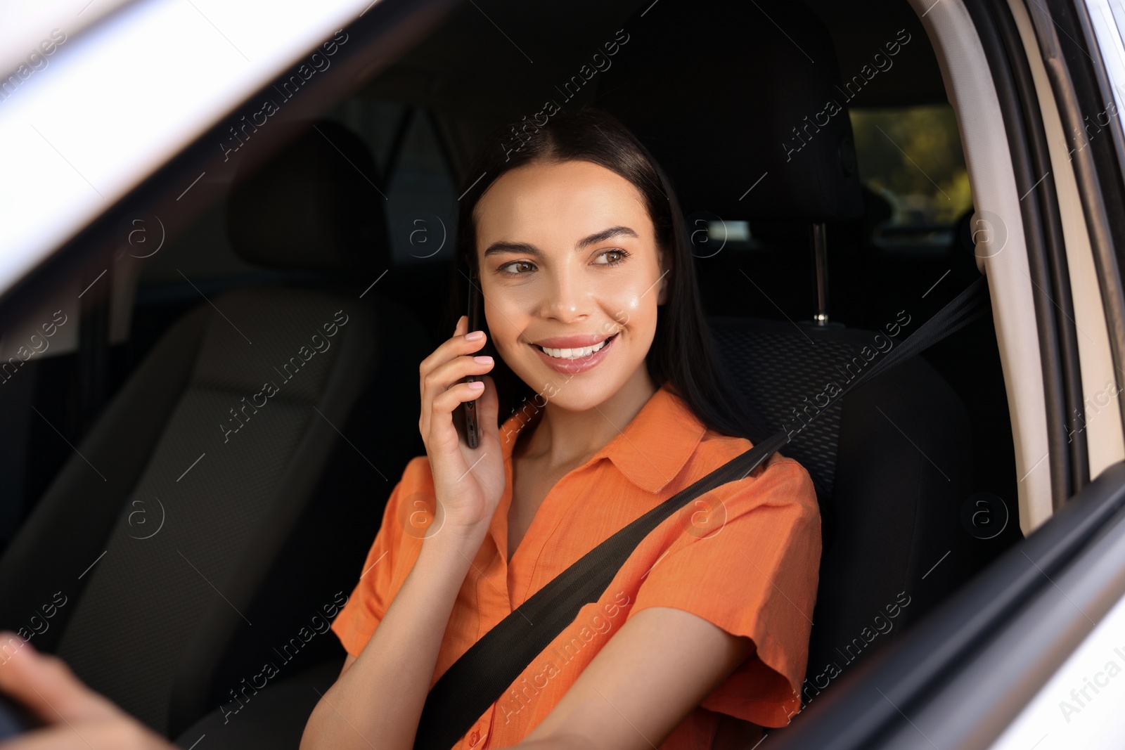 Photo of Happy young woman talking on smartphone in modern car, view from outside