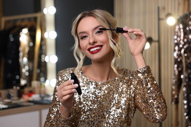 Photo of Beautiful makeup. Smiling woman applying mascara in dressing room