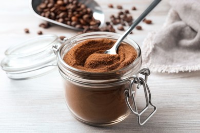 Photo of Jar of instant coffee and spoon on white wooden table