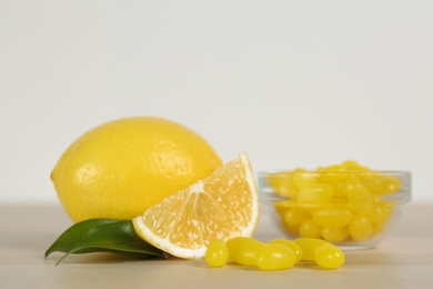 Photo of Fresh lemon and tasty small drops on wooden table