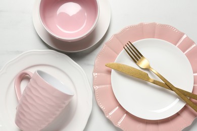 Beautiful ceramic dishware, cutlery and cup on white marble table, flat lay