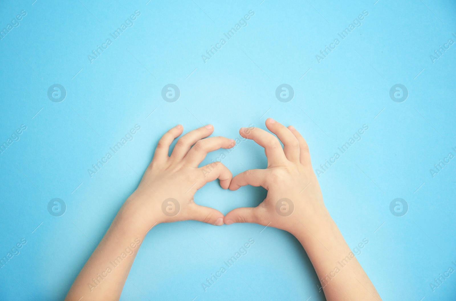 Photo of Child holding hands in shape of heart on color background. Happy Mother's Day