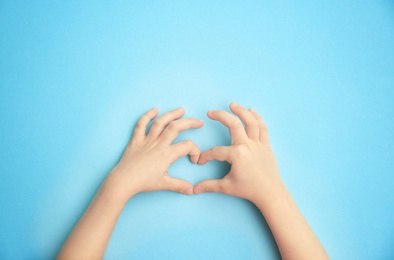 Photo of Child holding hands in shape of heart on color background. Happy Mother's Day