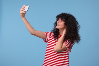 Photo of Beautiful young woman taking selfie on light blue background