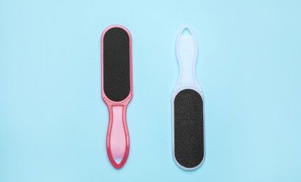 Photo of Foot files on light blue background, flat lay. Pedicure tools