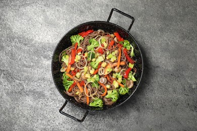 Photo of Stir fried noodles with mushrooms and vegetables in wok on grey table, top view