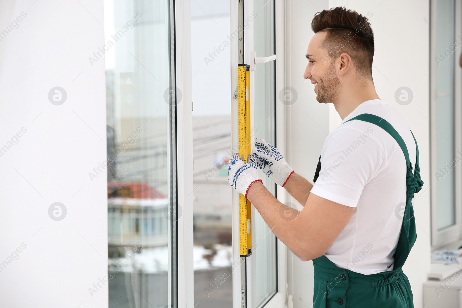 Photo of Construction worker using bubble level while installing window indoors