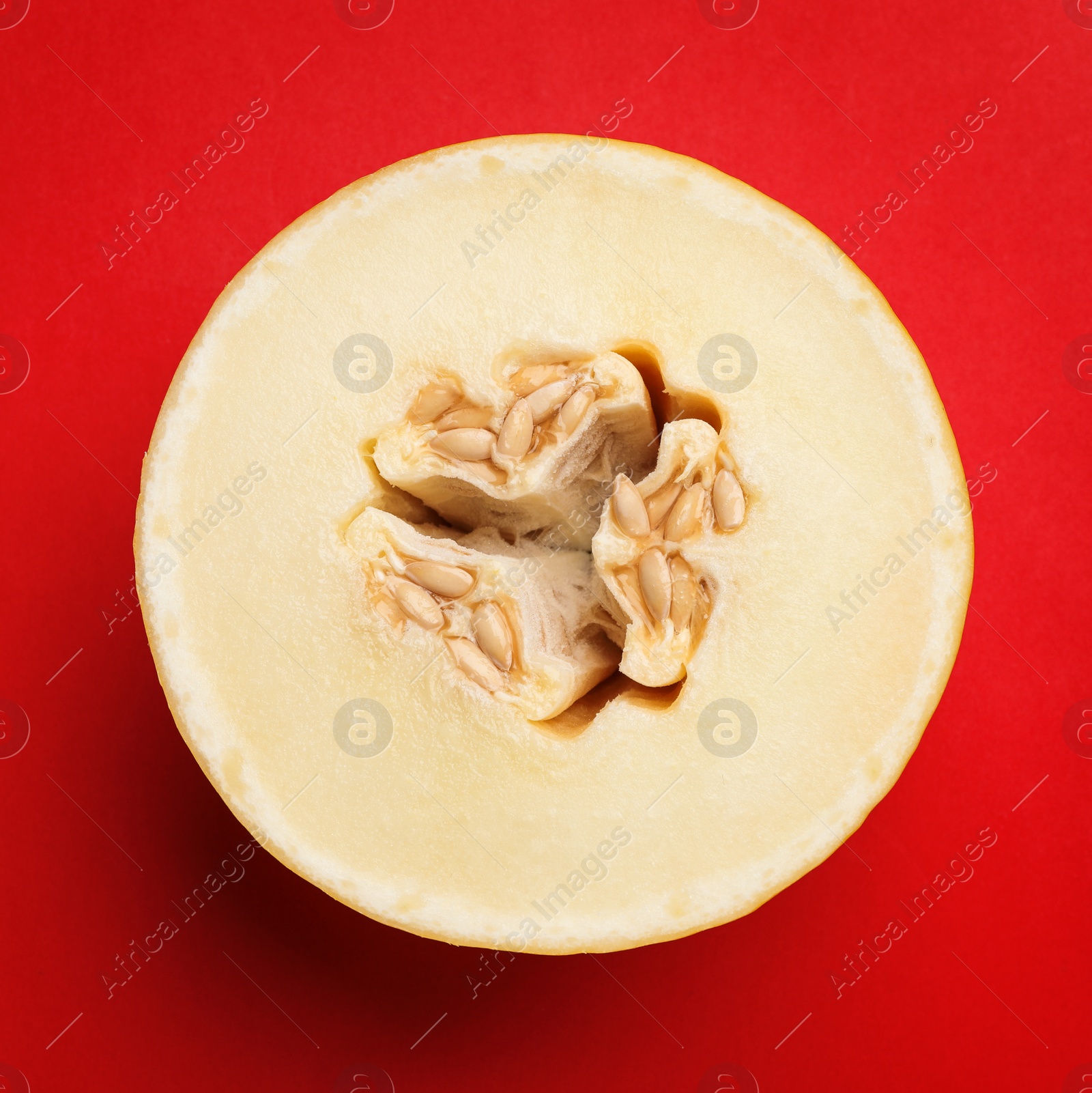 Photo of Half of ripe tasty melon on red background, top view