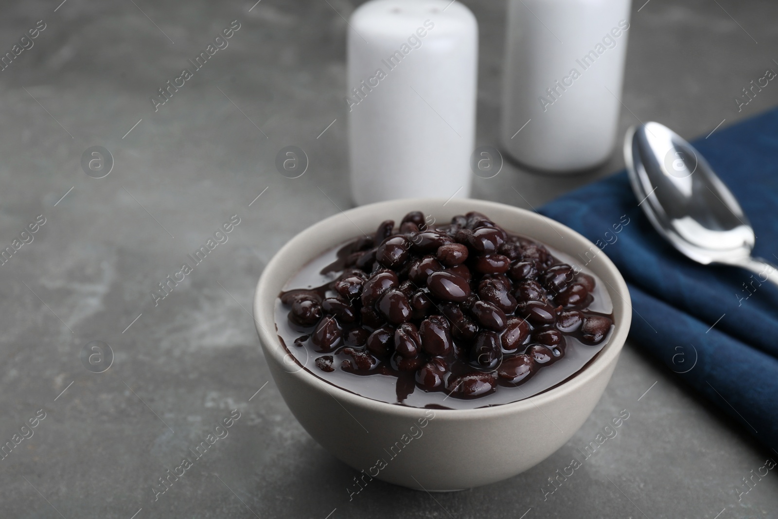 Photo of Bowl of canned kidney beans on grey table. Space for text