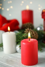 Photo of Burning candles on white wooden table against blurred festive lights. Christmas eve