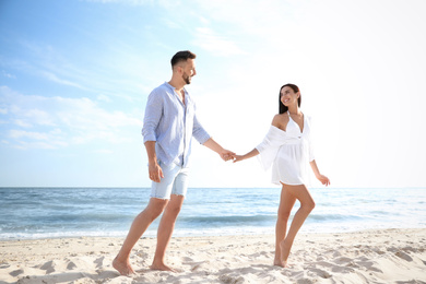 Happy young couple holding hands on beach