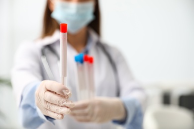 Doctor holding tubes with cotton swabs for DNA test in clinic, closeup