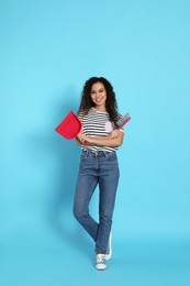 African American woman with broom and dustpan on light blue background