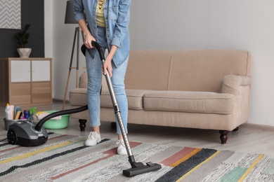 Young woman hoovering carpet at home