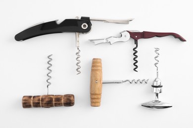 Different corkscrews on white background, flat lay