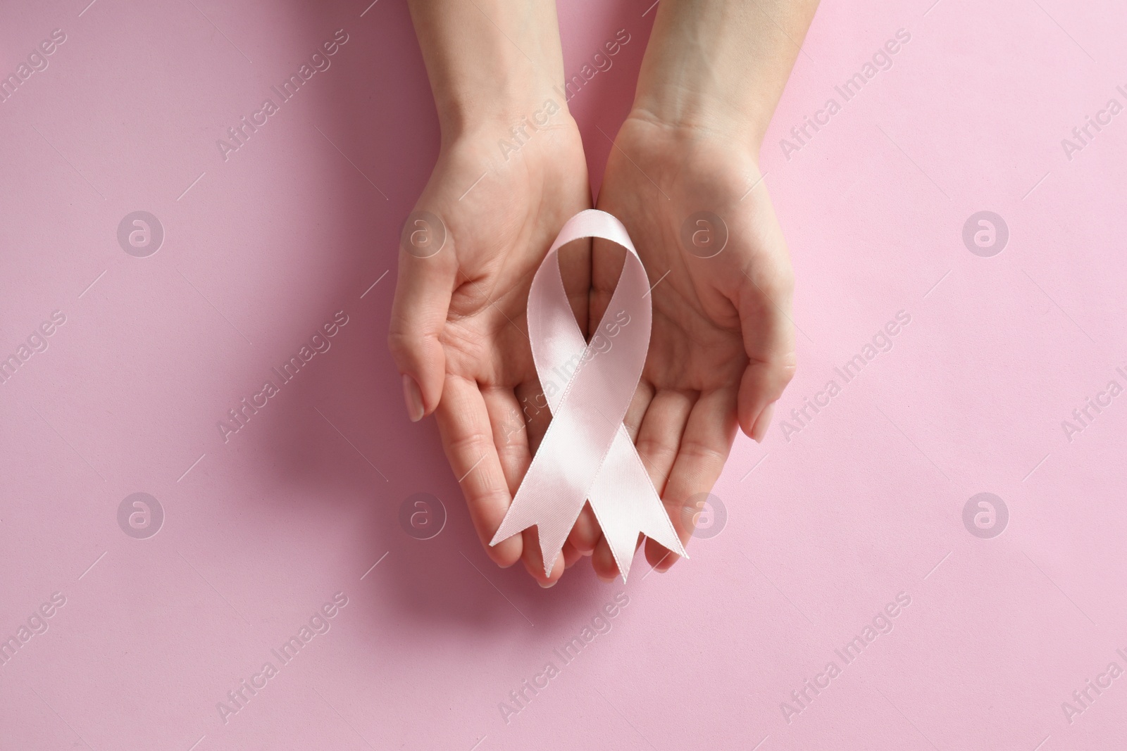 Photo of Woman holding pink ribbon on color background, top view. Breast cancer awareness