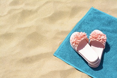 Photo of Towel and flip flops on sand, above view with space for text. Beach accessories