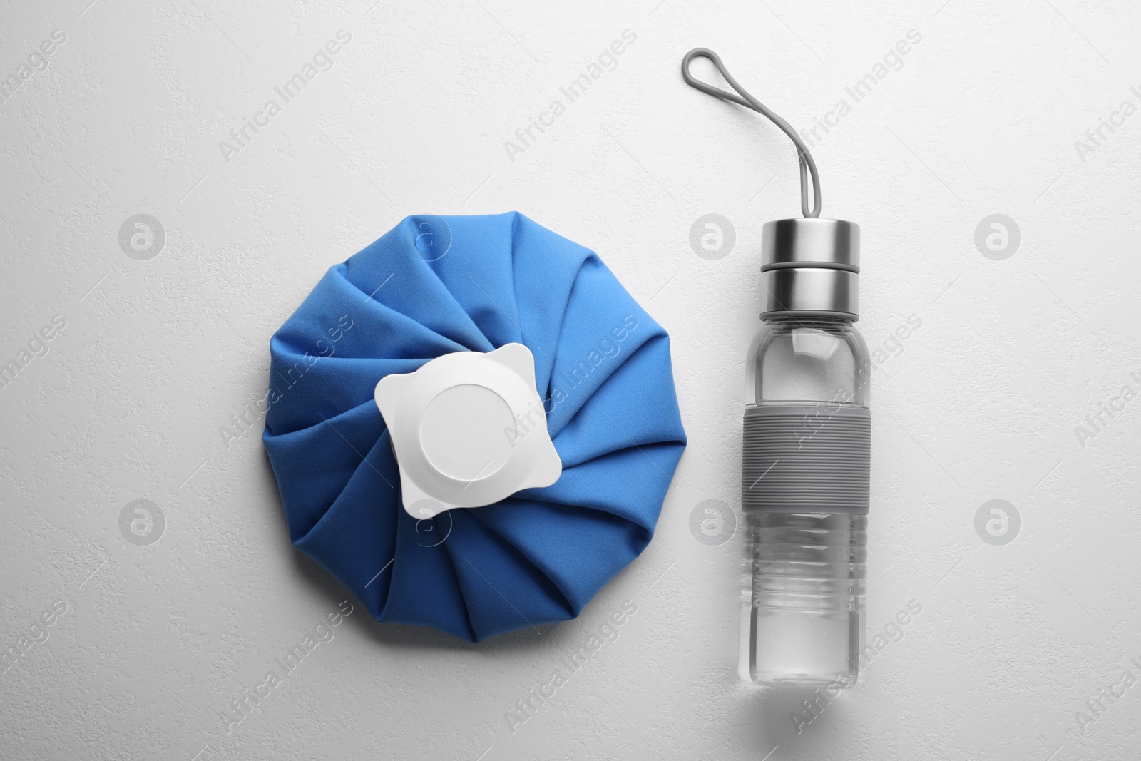 Photo of Bottle of water and cold compress on white background, flat lay. Heat stroke treatment