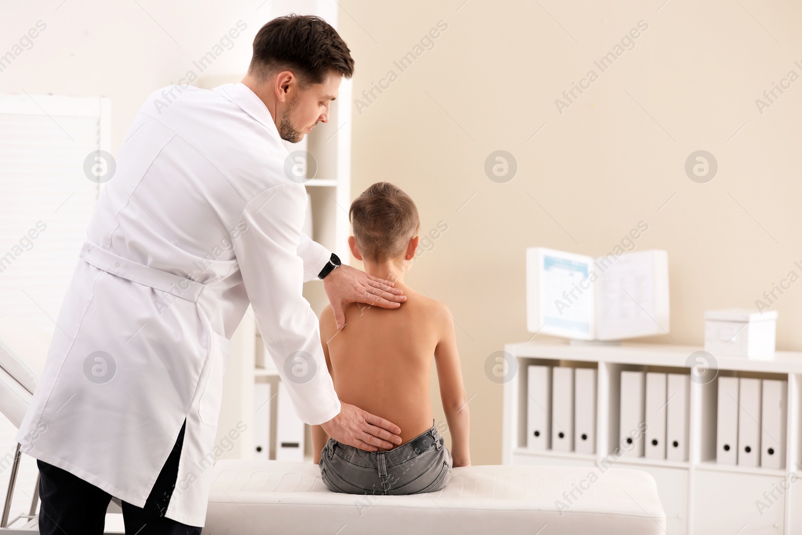 Photo of Chiropractor examining child with back pain in clinic