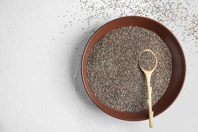 Plate and spoon with chia seeds on white background, top view. Space for text