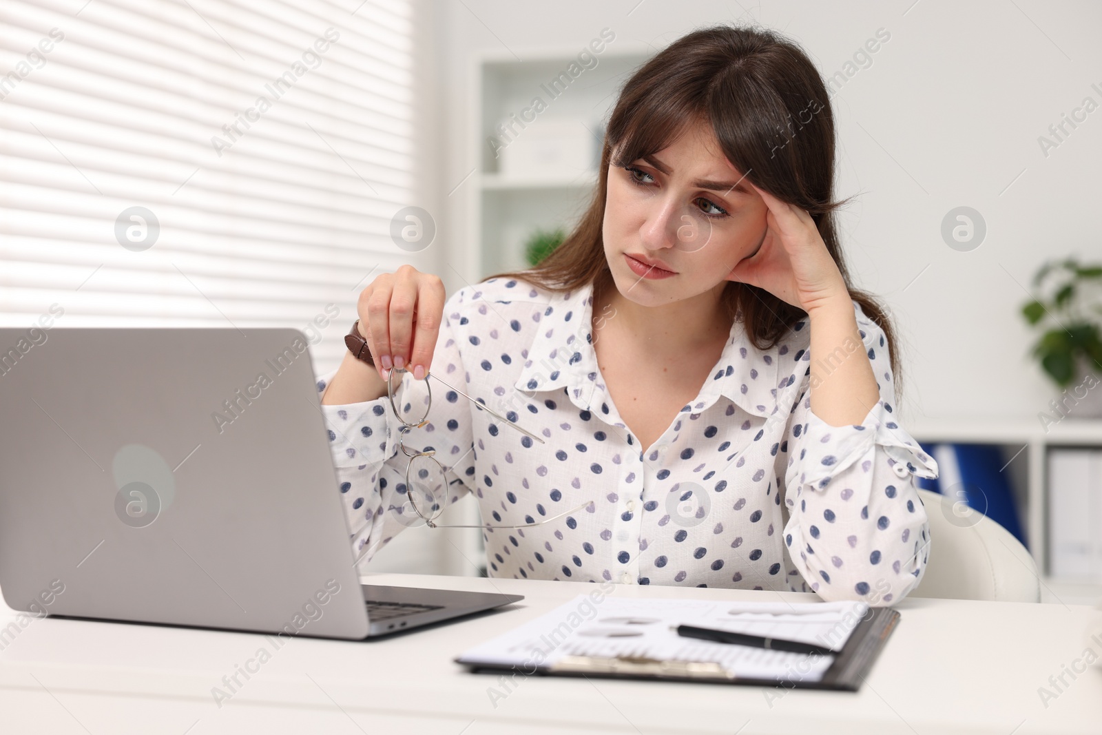 Photo of Overwhelmed woman sitting at table with laptop in office