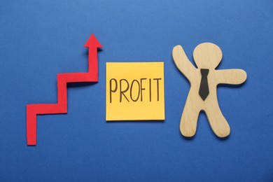 Photo of Sticky note with word Profit, up arrow and wooden human figure on blue background, flat lay