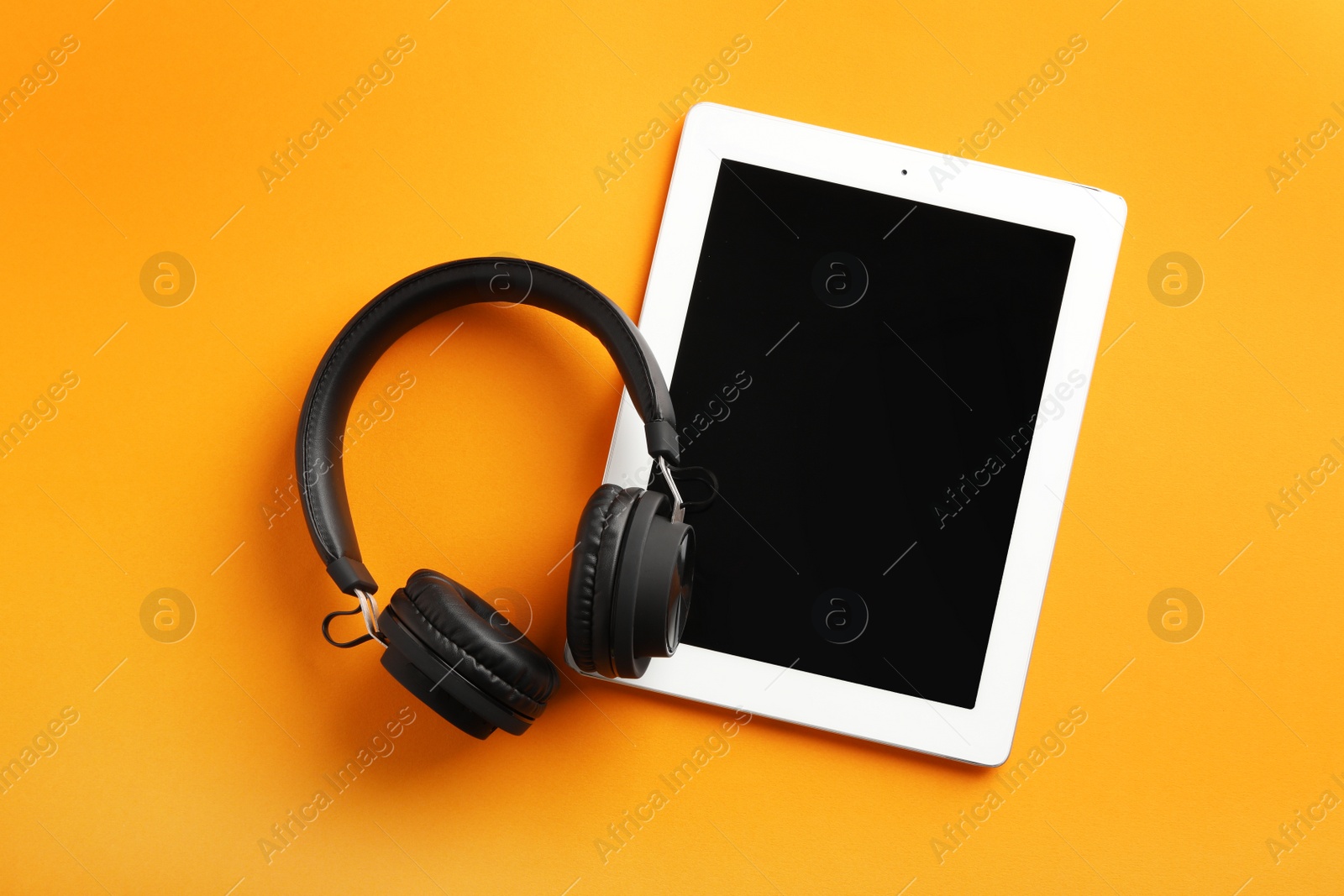 Photo of Stylish headphones and modern tablet on color background, flat lay. Space for text