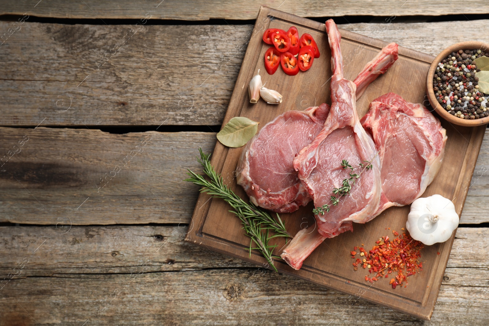 Photo of Fresh tomahawk beef cuts and spices on wooden table, top view. Space for text