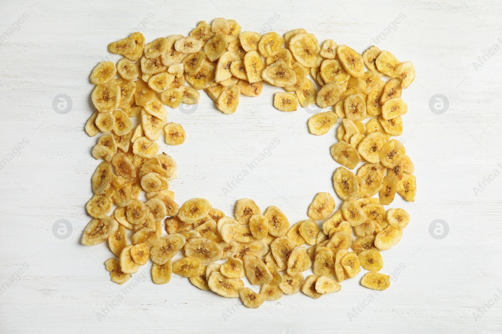 Photo of Frame made of sweet banana slices on wooden background, top view with space for text. Dried fruit as healthy snack