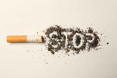 Photo of Burnt cigarette and word Stop made of ash on white table, flat lay. No smoking concept