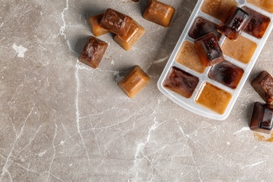 Photo of Coffee ice cubes and tray on grey table, flat lay. Space for text
