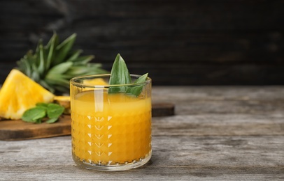 Photo of Glass with delicious pineapple juice on table