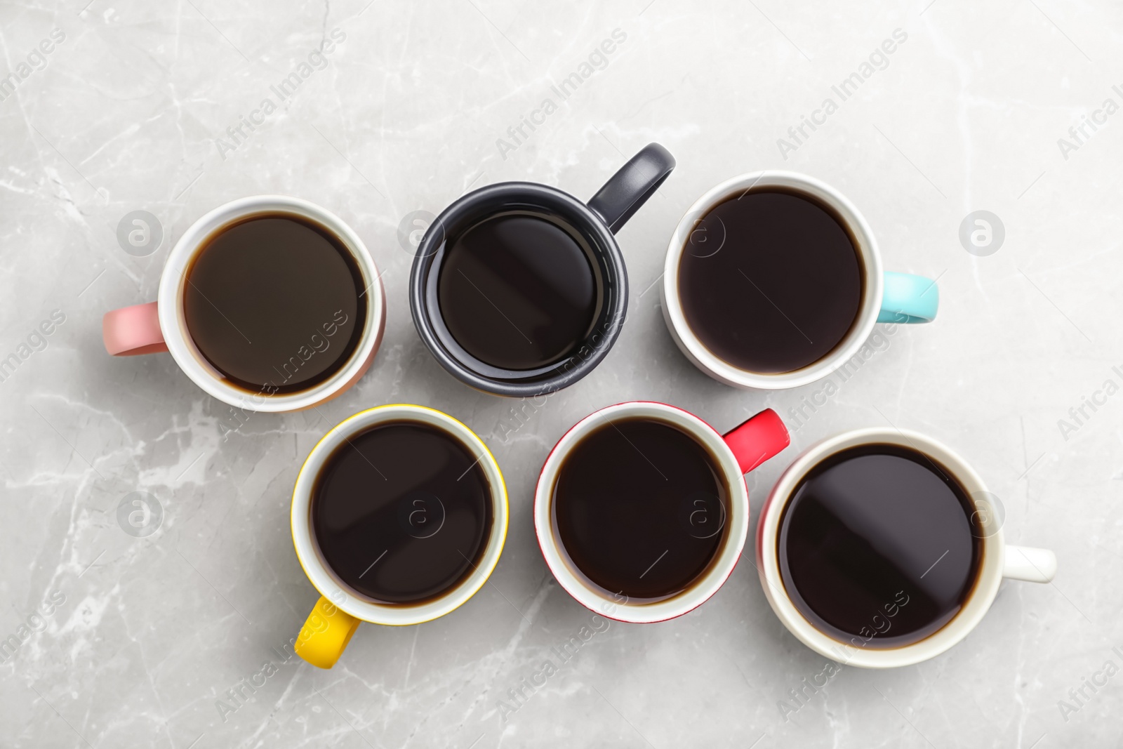 Photo of Many ceramic cups with hot aromatic coffee on marble background, flat lay