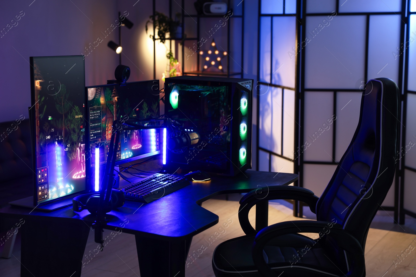 Photo of Playing video games. Stylish room interior with modern computer and gaming chair in neon lights