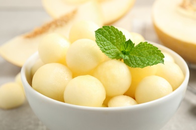 Photo of Melon balls and mint in bowl on table, closeup