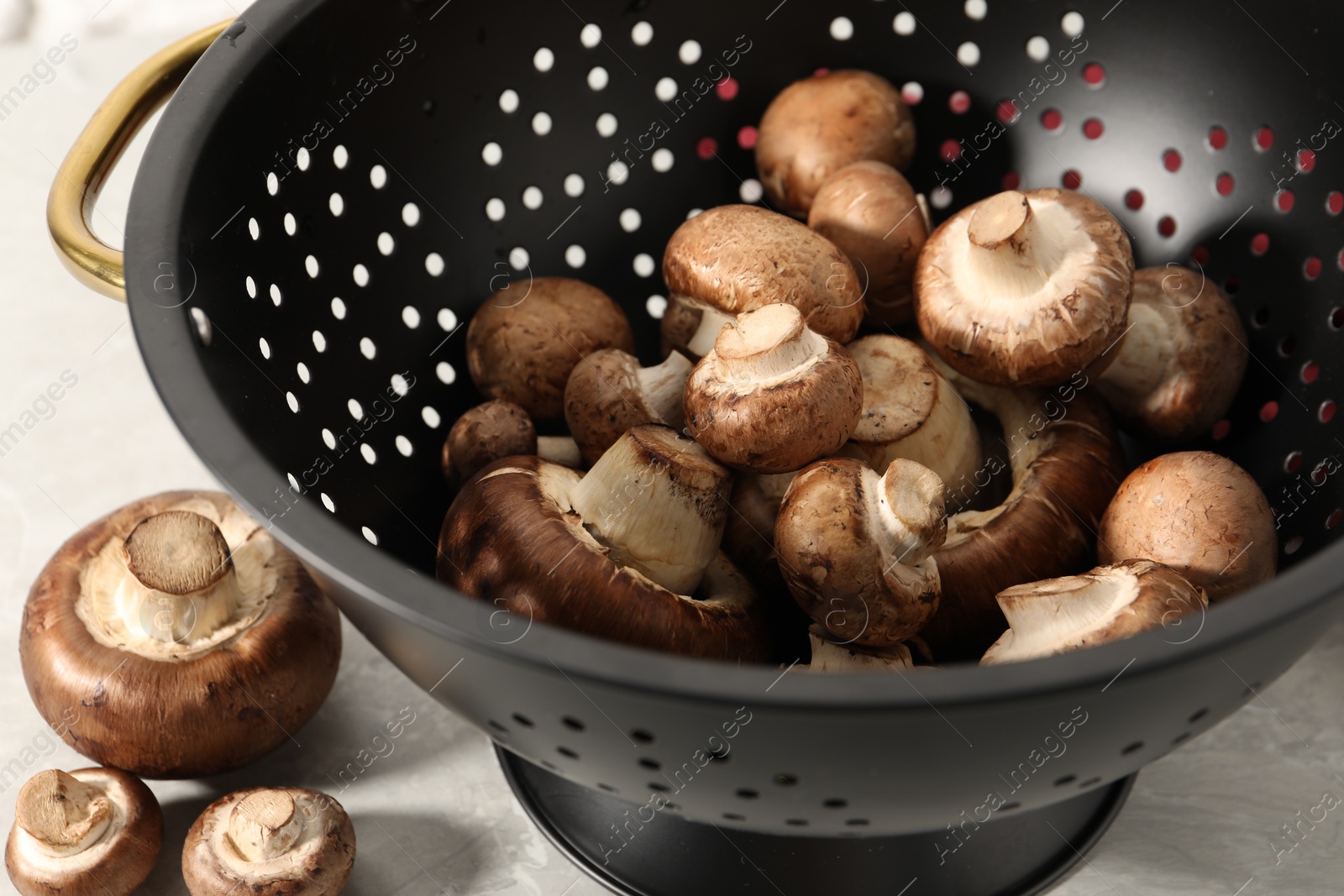 Photo of Raw mushrooms in black colander on table, closeup