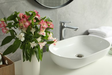 Photo of Vase with beautiful Alstroemeria flowers near sink in bathroom