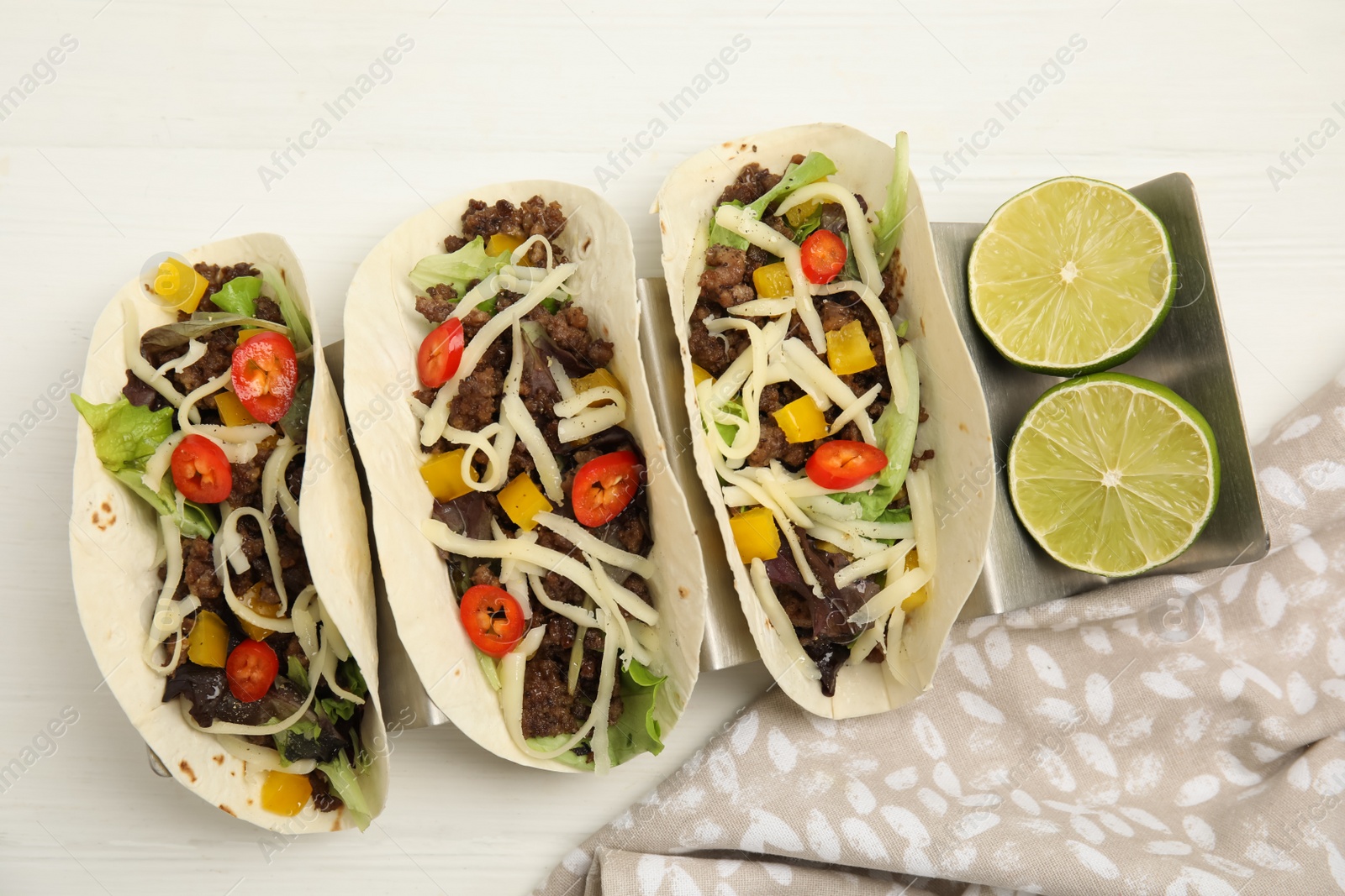 Photo of Delicious tacos with fried meat, vegetables and cheese on white wooden table, flat lay