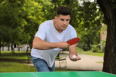 Man playing ping pong in park on summer day