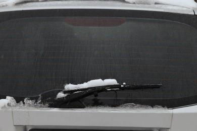 Car window cleaned from snow with rear wiper blade outdoors on winter day