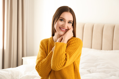 Photo of Young woman wearing warm sweater on bed at home. Winter season