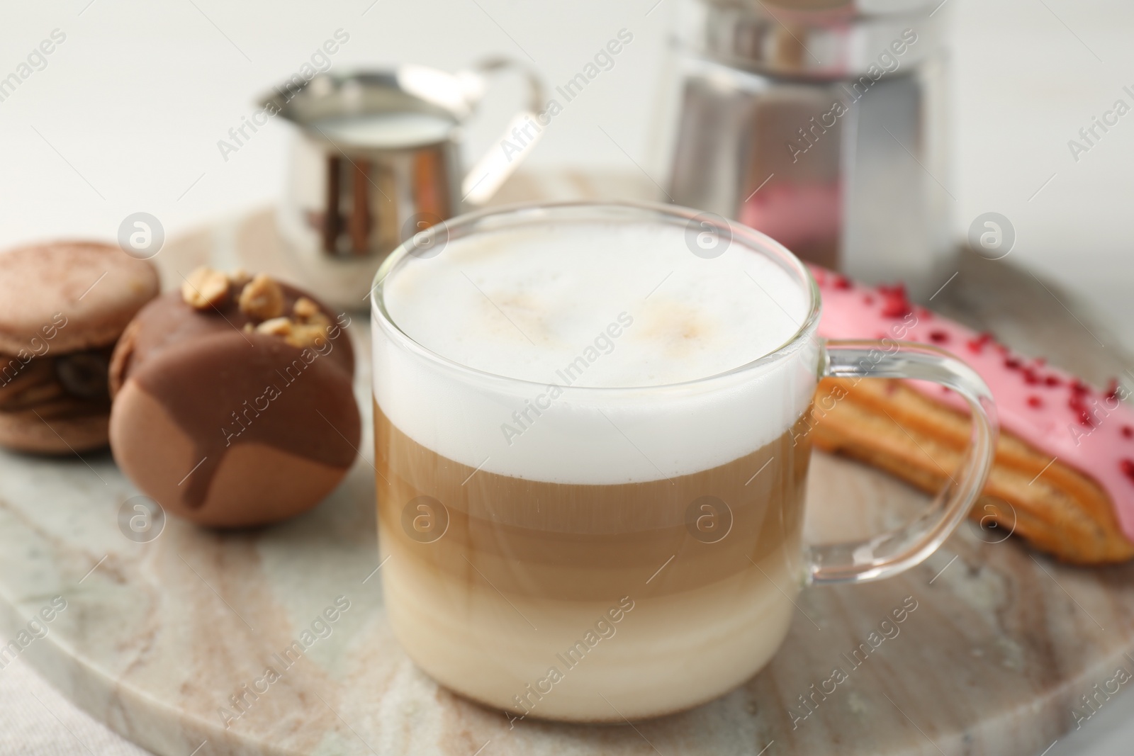 Photo of Aromatic coffee in cup, tasty macarons and eclair on table, closeup