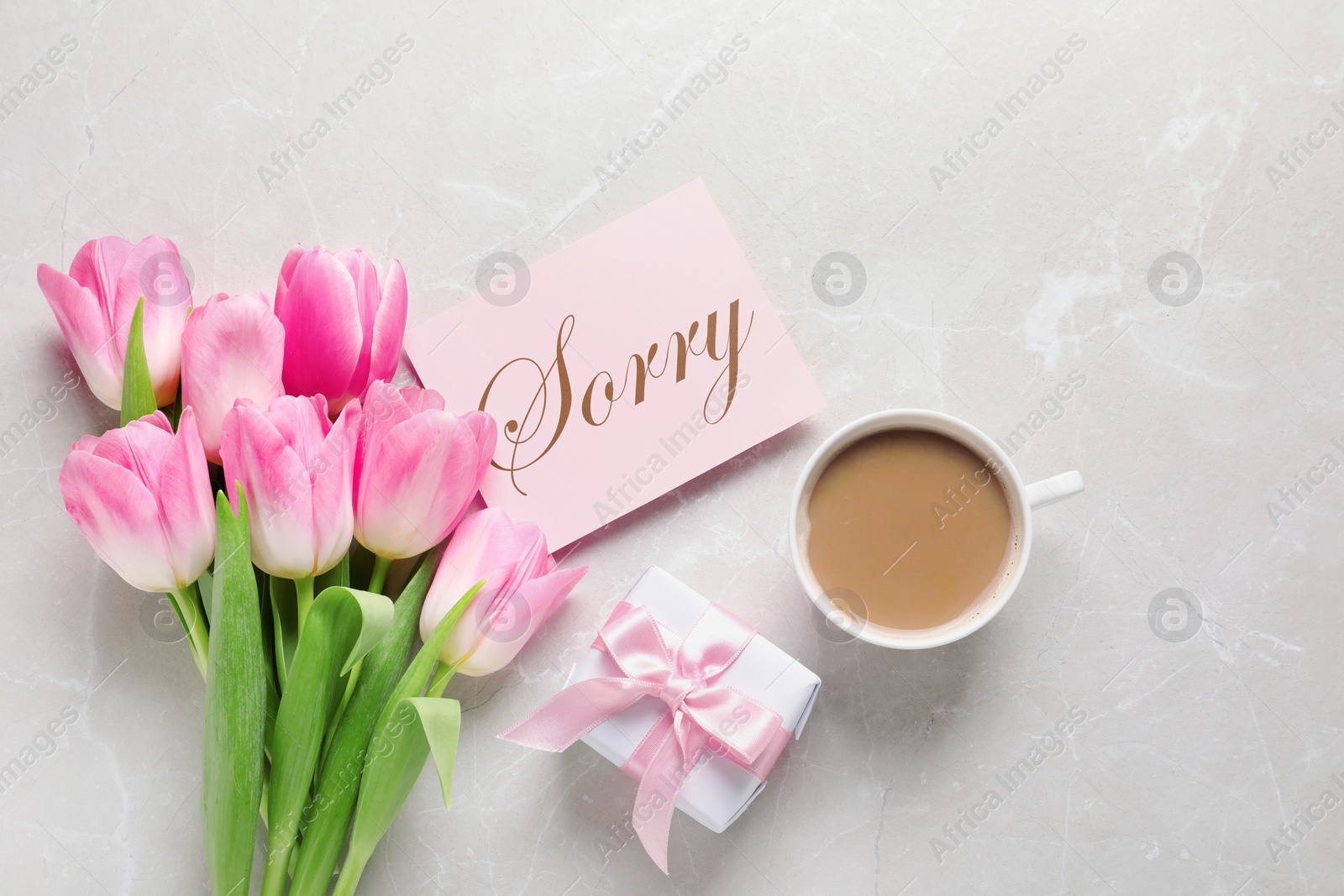 Image of Card with word Sorry, cup of coffee, gift box and bouquet of tulips on light grey marble table, flat lay