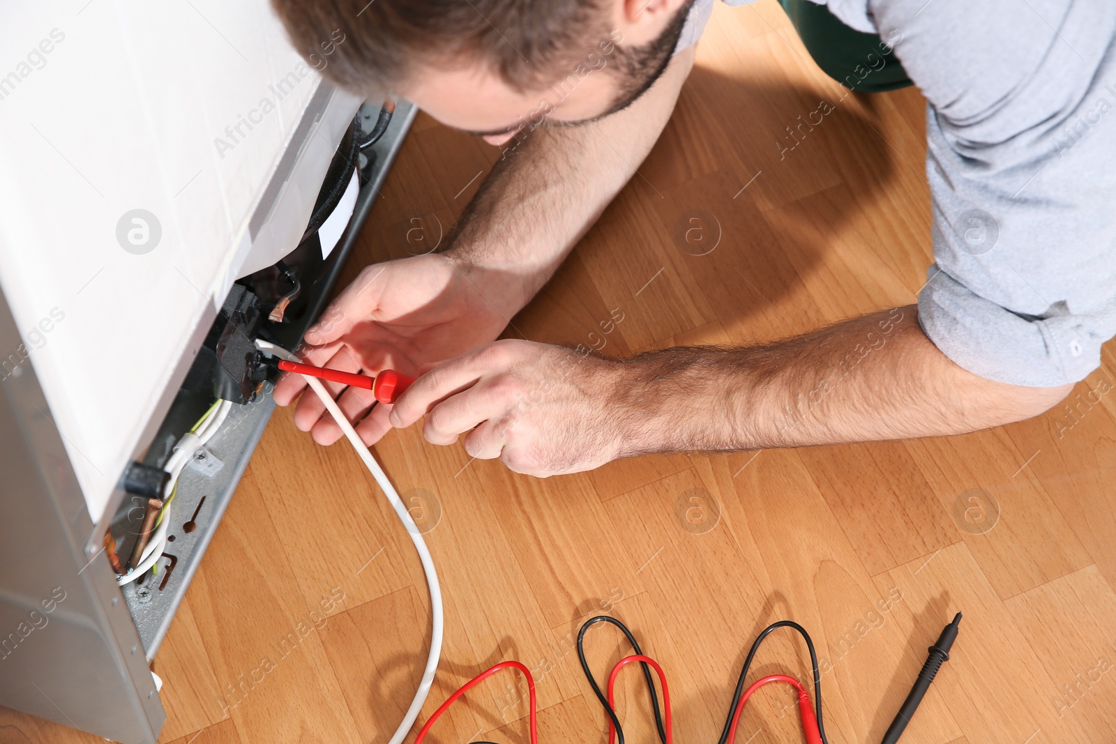 Photo of Male technician repairing broken refrigerator indoors, closeup