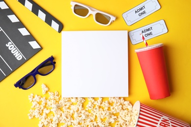 Photo of Flat lay composition with blank paper, popcorn and clapper on color background, mockup for design. Watching cinema