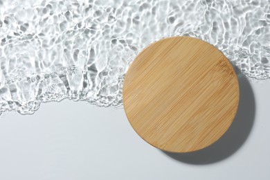 Photo of Presentation of product. Wooden podium in water on white background, top view. Space for text