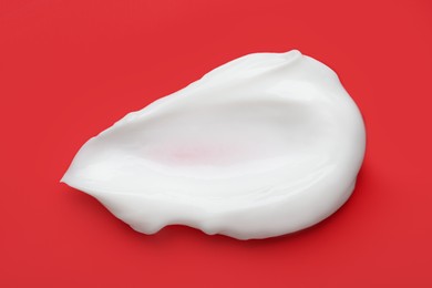 Photo of Body cream sample on red background, closeup. Cosmetic product