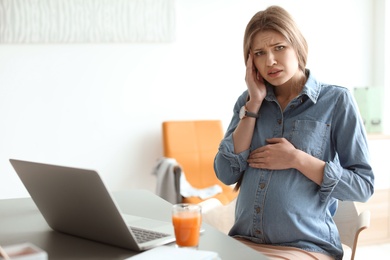 Photo of Pregnant woman suffering from headache at workplace