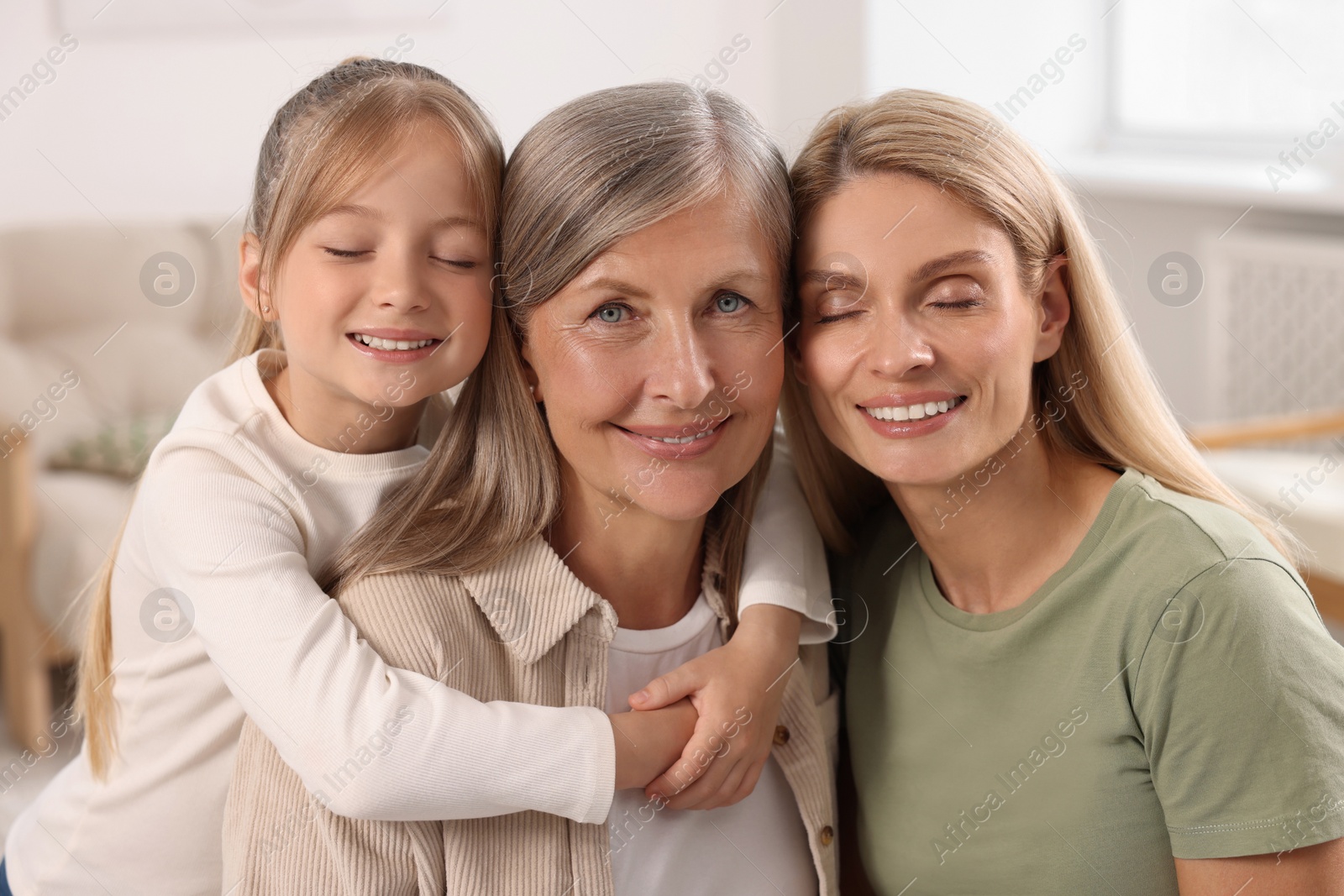 Photo of Three generations. Happy grandmother, her daughter and granddaughter at home