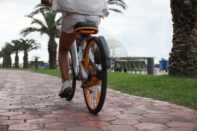 Photo of Young woman riding bicycle on lane outdoors, back view